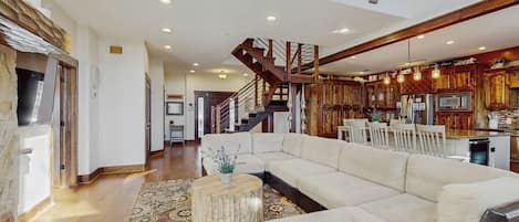 A spacious living area with a large sectional sofa, a round coffee table, and a patterned rug.