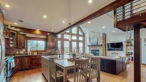 Une cuisine spacieuse dotée de meubles en bois, d’un grand îlot central et d’un coin repas avec des chaises.