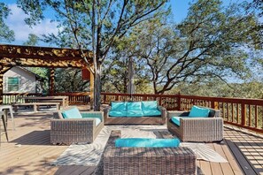 Una terraza de madera con mobiliario de mimbre y una pérgola.