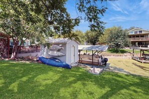 A backyard with a small shed, a covered seating area, and a blue inflatable raft. - Dog-friendly Home w/ a Furnished Patio, Free Wifi, & Central A/C - Near Cove (Kingsland)