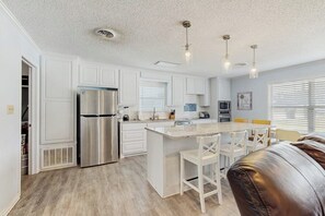 A modern kitchen with white cabinetry, a stainless steel refrigerator, a central island with bar stools, and pendant lighting. - Dog-friendly Home w/ a Furnished Patio, Free Wifi, & Central A/C - Near Cove (Kingsland)