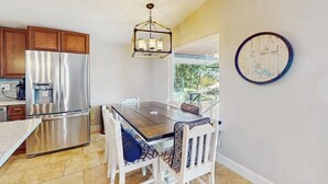 Una cocina con electrodomésticos de acero inoxidable, una mesa de comedor con sillas y una lámpara colgante.