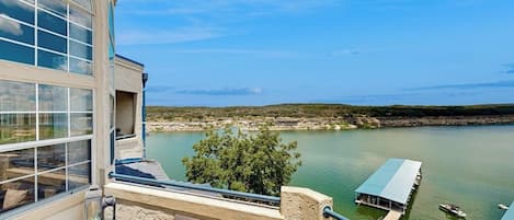 Un balcón con mobiliario de mimbre, vistas a un lago y un muelle para embarcaciones.