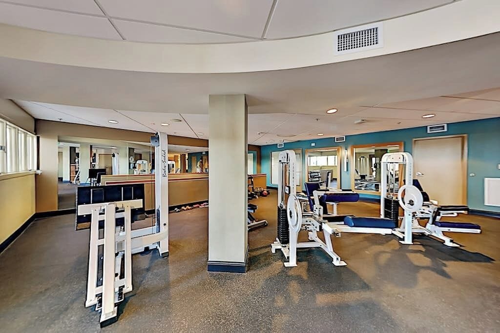 A gym with exercise equipment, a reception desk, and a mirror.