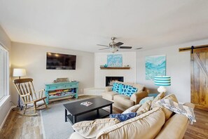 A living room with a sofa, coffee table, rocking chair, fireplace, and a sign that says 'Go Jump in the Lake'. - Dog-friendly Lakefront Home With Private Sundeck (Kingsland)