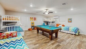 A room with a pool table, bunk beds, and a ceiling fan.