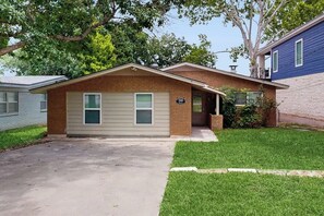 A single-story house with a front porch, a brick chimney, and a small front yard. - Dog-friendly Lakefront Home With Private Sundeck (Kingsland)
