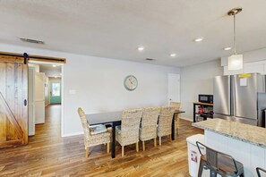 A modern kitchen with a dining area, wooden flooring, and a clock on the wall. - Dog-friendly Lakefront Home With Private Sundeck (Kingsland)