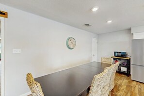 A dining area with a table and chairs, a clock on the wall, a microwave, and a refrigerator. - Dog-friendly Lakefront Home With Private Sundeck (Kingsland)