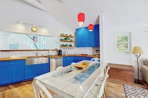 A modern kitchen with blue cabinets, a glass dining table, and a red pendant light. - Lakefront Home on Water With Great Views, Boat Dock, Al Fresco Dining, and Wifi (Kingsland)