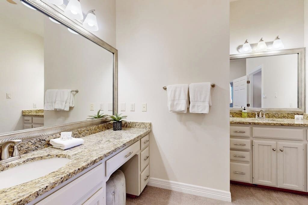 A bathroom with a granite countertop, a large mirror, and a sink.