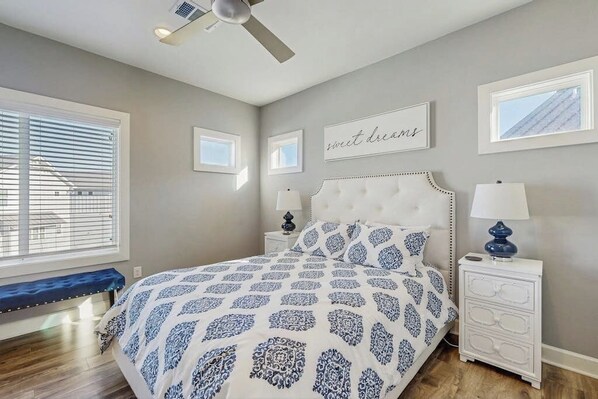 A bedroom with a bed, a bench, a ceiling fan, a nightstand, and wall art. - Stunning Lakefront Home With Pickleball, Shared Pool & Sand Volleyball (Kingsland)