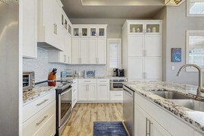 A modern kitchen with white cabinetry, a granite countertop, and a built-in oven. - Stunning Lakefront Home With Pickleball, Shared Pool & Sand Volleyball (Kingsland)