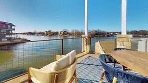 A balcony with a view of a body of water, a table, and two chairs. - Stunning Lakefront Home With Pickleball, Shared Pool & Sand Volleyball (Kingsland)