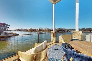 A balcony with a view of a body of water, a table, and two chairs. - Stunning Lakefront Home With Pickleball, Shared Pool & Sand Volleyball (Kingsland)