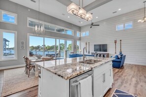 A spacious kitchen with a large island, a dining area with a view, and a living room with a TV and seating. - Stunning Lakefront Home With Pickleball, Shared Pool & Sand Volleyball (Kingsland)