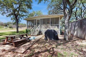 Ein überdachter Außenbereich mit Picknicktisch, überdachter Grillstation und einem Moskitonetz-Vorbau.