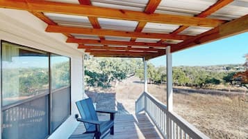 Un espacio al aire libre cubierto con vigas de madera, un banco y vistas a un viñedo.