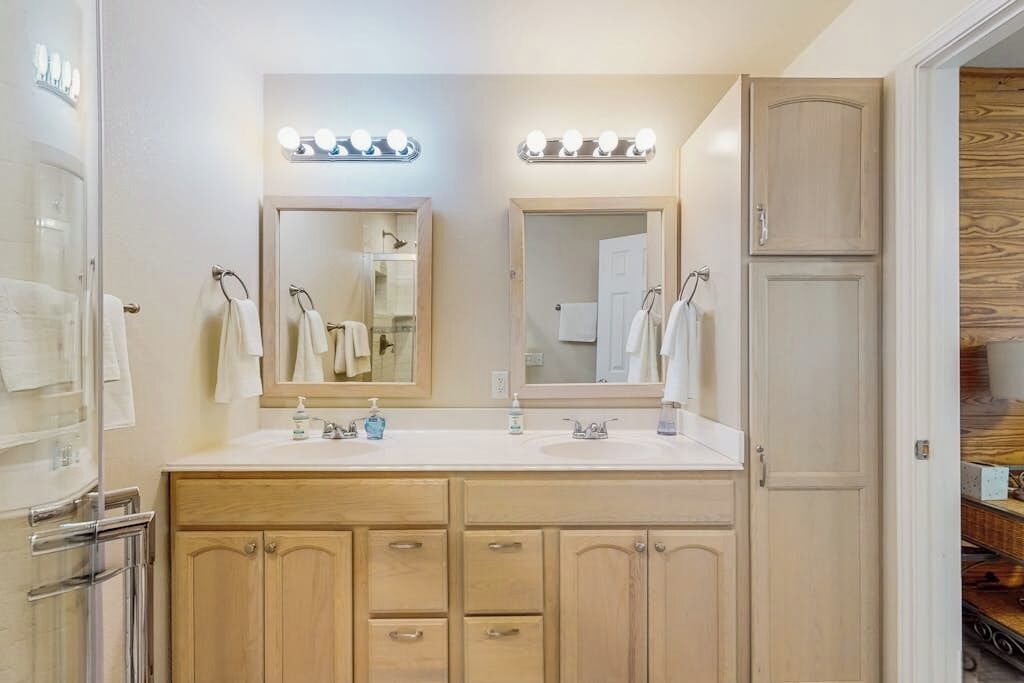 A bathroom with two sinks, mirrors, and vanity cabinets.