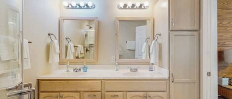 A bathroom with two sinks, mirrors, and vanity cabinets.