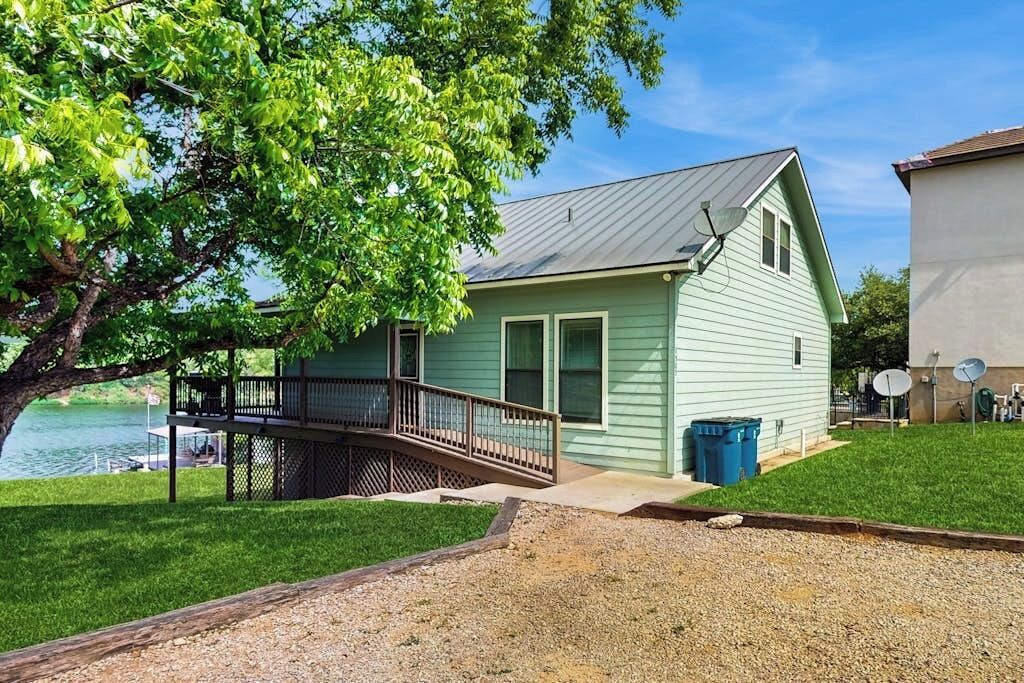 A light green house with a balcony, a dock, and a lake view.