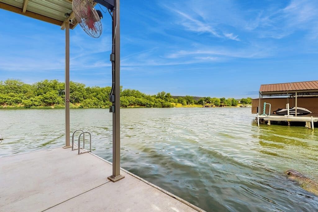 A dock extending into a body of water with a covered area and a building with a metal roof.