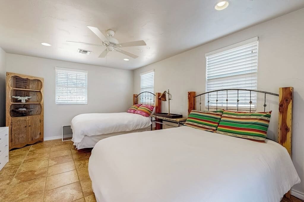 Une chambre avec deux lits, un ventilateur de plafond et une armoire en bois.