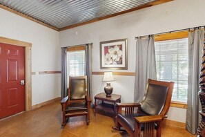 A room with a wooden door, two leather chairs, a small table with a lamp, and a framed picture on the wall. - Dog-friendly Cottage on Hwy 290 Wine Trail (Fredericksburg)