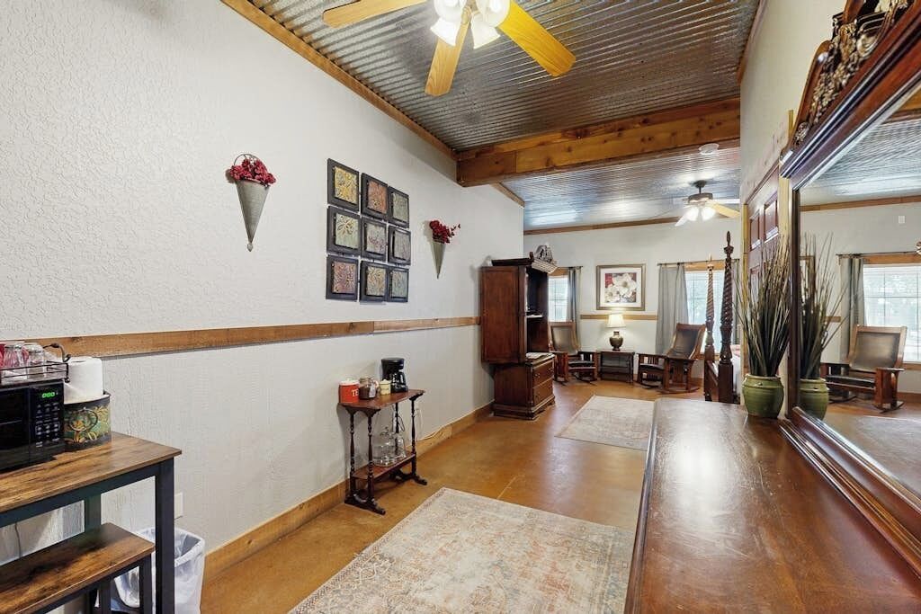 Una habitación amplia con techo de madera, un espejo grande, una zona de comedor y una cocina.