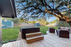 A deck with outdoor furniture, a hot tub, and a tree. - Blue Haus With Hot Tub, Shuffleboard, EV Charger - Walk to Town & Wineries (Johnson City)