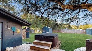 A backyard with a hot tub, a wooden deck, and a covered patio area. - Blue Haus With Hot Tub, Shuffleboard, EV Charger - Walk to Town & Wineries (Johnson City)