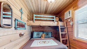 A bunk bed with a ladder, a small window with blinds, a wall-mounted heater, and a framed picture on the wall. - Amazing Hill Country Cabin With Canyon Views, Furnished Deck, Grill, & AC (Fredericksburg)