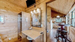 A wooden cabin interior with a bathroom, a dining area, and a kitchen. - Amazing Hill Country Cabin With Canyon Views, Furnished Deck, Grill, & AC (Fredericksburg)