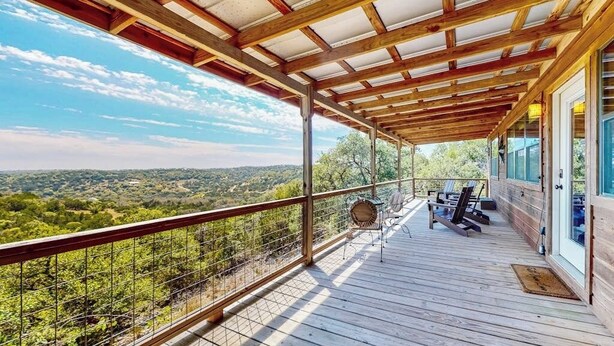 A wooden deck with a view of a mountainous landscape, a covered area with chairs, and a railing. - Amazing Hill Country Cabin With Canyon Views, Furnished Deck, Grill, & AC (Fredericksburg)