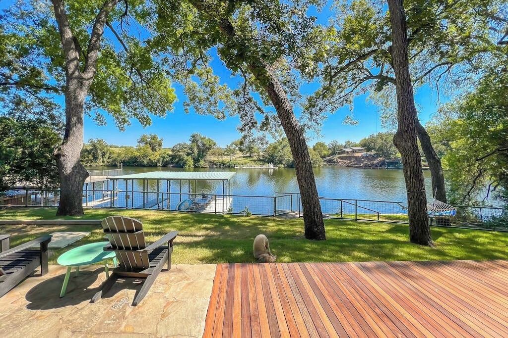 A wooden deck with outdoor furniture, a view of a lake, and a covered area with a railing.