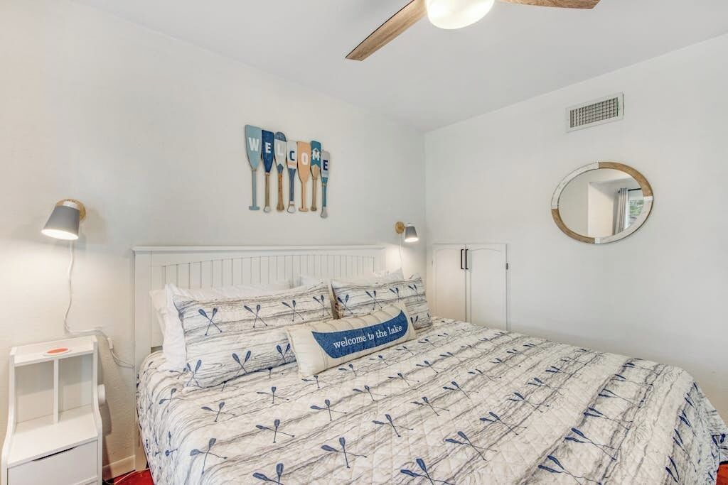 Ein Schlafzimmer mit Bett, Nachttisch, Deckenventilator, Wandspiegel und Wanddeko mit Schlägern.