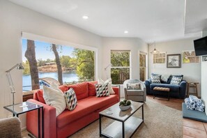 A living room with a red sofa, a grey armchair, a blue sofa, a coffee table, and a TV. - Two-story Waterfront Retreat With Boat Dock, Two Firepits & Two Kayaks (Buchanan Dam)