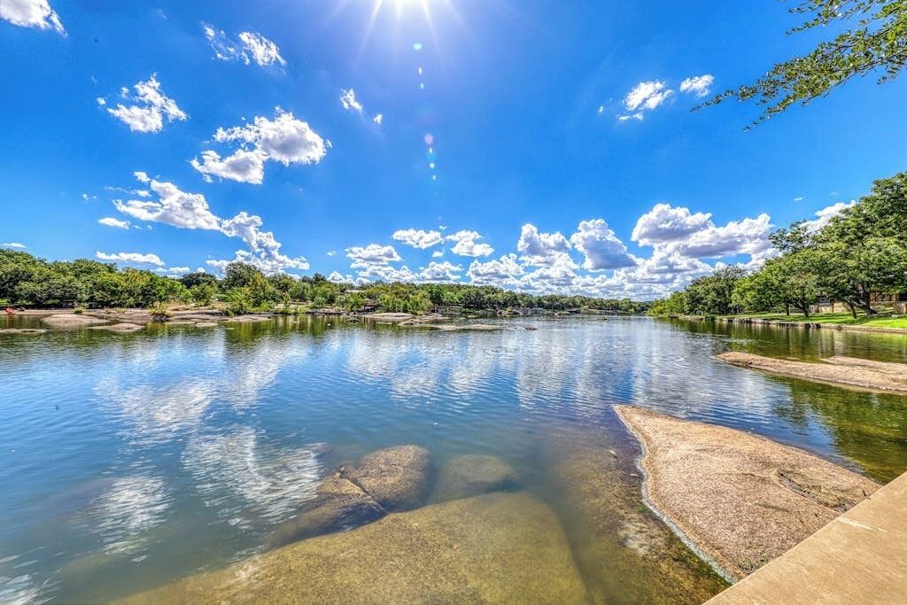 A river with clear water, surrounded by trees and a clear sky.