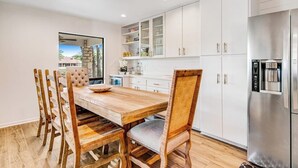A modern kitchen with white cabinets, a stainless steel refrigerator, and a wooden dining table with chairs. - Spacious & Elegant Haven With Huge Yard, Updated Interior, AC, & Fast Wifi (Horseshoe Bay)