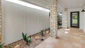 A covered outdoor area with stone pillars, a tiled floor, and a white wall. - Spacious & Elegant Haven With Huge Yard, Updated Interior, AC, & Fast Wifi (Horseshoe Bay)
