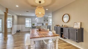 A spacious kitchen with a wooden dining table, a hanging light fixture, and a cabinet with a mirror and a sign. - Peaceful Riverfront Home With Enclosed Yard - Walk to the River (Liberty Hill)