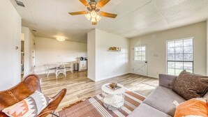 A spacious living room with a ceiling fan, a sofa, a coffee table, and a dining area in the background. - Cozy Home Near River Access With Firepit & Playground (Liberty Hill)