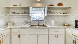 A kitchen with white cabinets, a double sink, and a window above the sink. - Cozy Home Near River Access With Firepit & Playground (Liberty Hill)