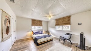 A bedroom with a bed, a chair, a desk, a ceiling fan, and windows with blinds. - Cozy Home Near River Access With Firepit & Playground (Liberty Hill)