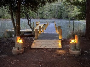 A wooden pathway leading to a seating area with benches, surrounded by trees and a body of water. - Driftwood Cove Waterfront/Dock/Game house (Miles)