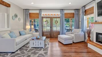 Un salón espacioso con un sofá blanco, un sillón blanco, una mesa de centro y una chimenea.