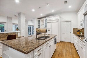 Eine moderne Küche mit Granit Arbeitsplatten, weißen Schränken und einer doppelten Spüle.