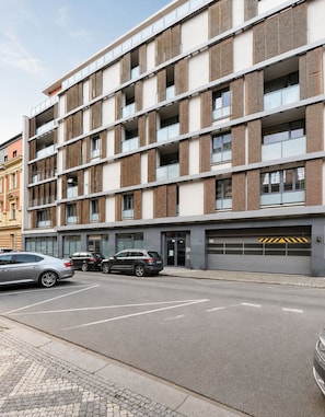 Ein mehrstöckiges Gebäude mit modernem architektonischen Design, das Ziegel und Glas in der Fassade kombiniert, mit einer Tiefgarage im Erdgeschoss.