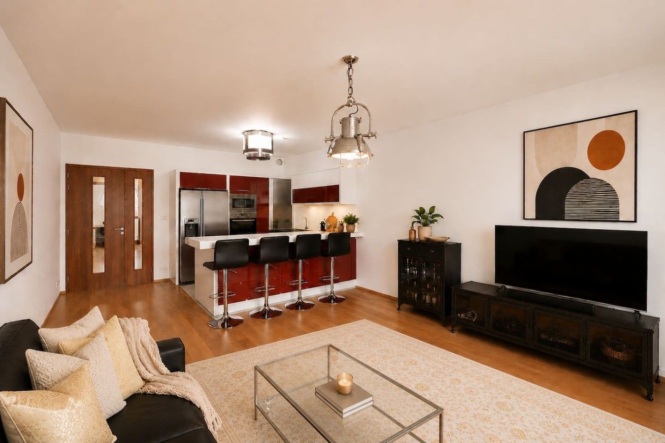 A modern living room with a sofa, a coffee table, a TV, and a kitchen area with a bar.