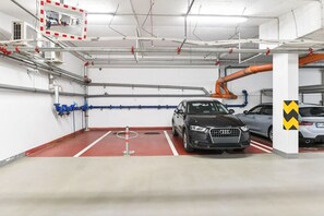 A parking garage with multiple levels, visible pipes, and a red floor. - Central location, 2Bedrooms, Free Parking, Balcony (Prague 5)